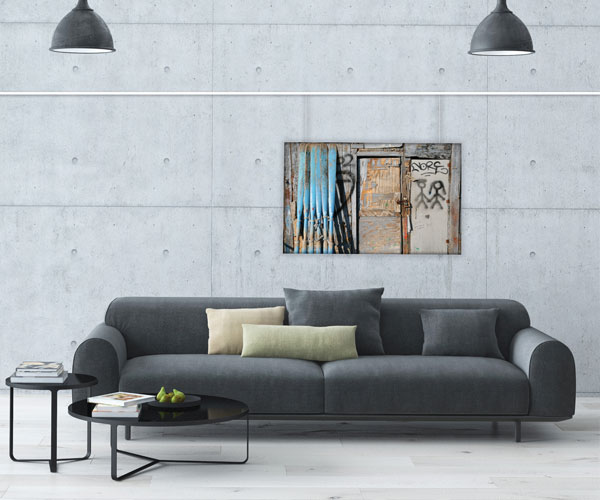 A sleek gray couch located in front of an artistic painting hanging from a picture rail, contributing to a modern interior design.